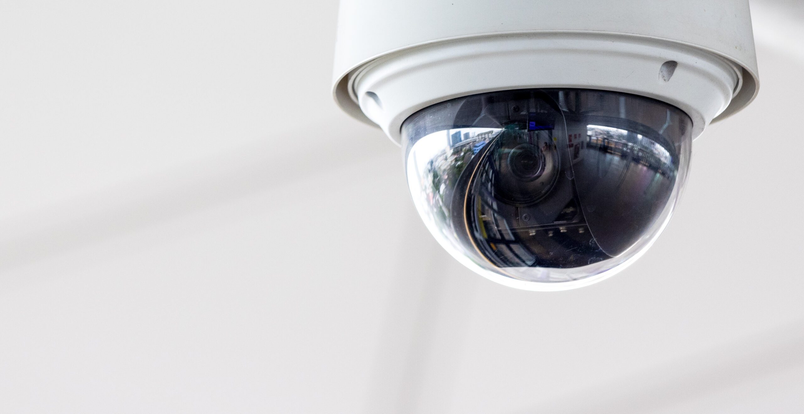 Closeup,Of,White,Dome,Type,Cctv,Digital,Security,Camera,Installed Outdoor security camera mounted on a white wall.